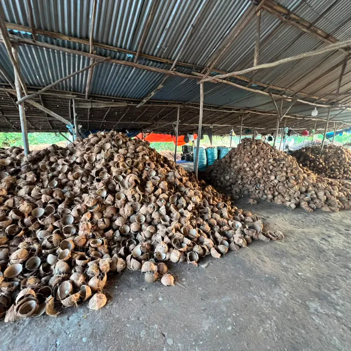 Covered supply shed holding several coconut shell stockpiles